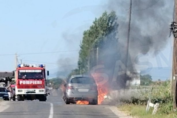foto masina cuprinsa de flacari nor dens de fum langas trecerea la nivel cu calea ferata