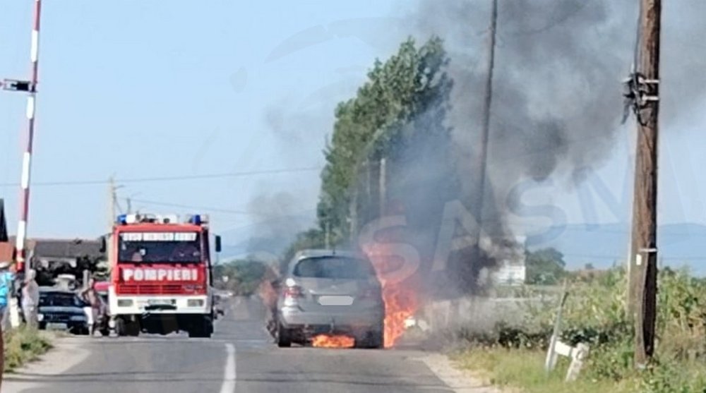 foto masina cuprinsa de flacari nor dens de fum langas trecerea la nivel cu calea ferata